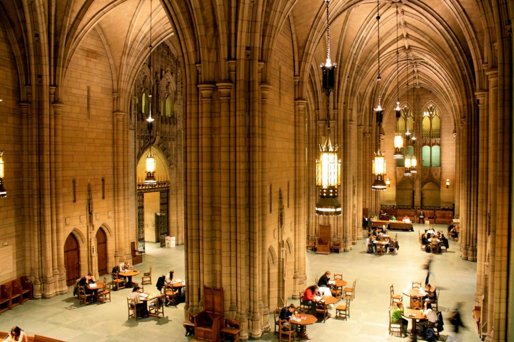 inside the cathedral of learning at the university of pittsburgh, stone columns dwarf the students reading at tables below