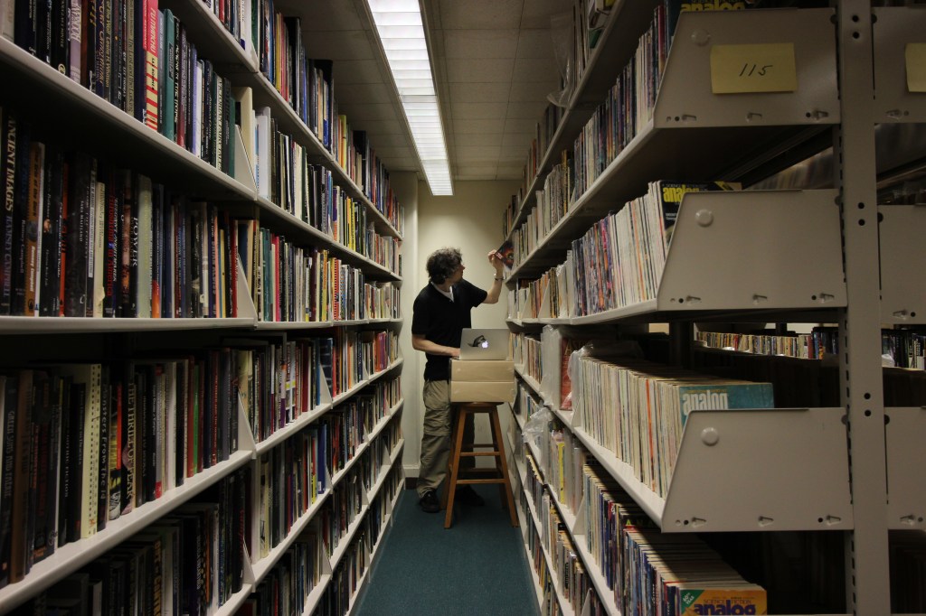 Jason Ellis cataloging Science Fiction magazines with his laptop in the City Tech Library Archives.