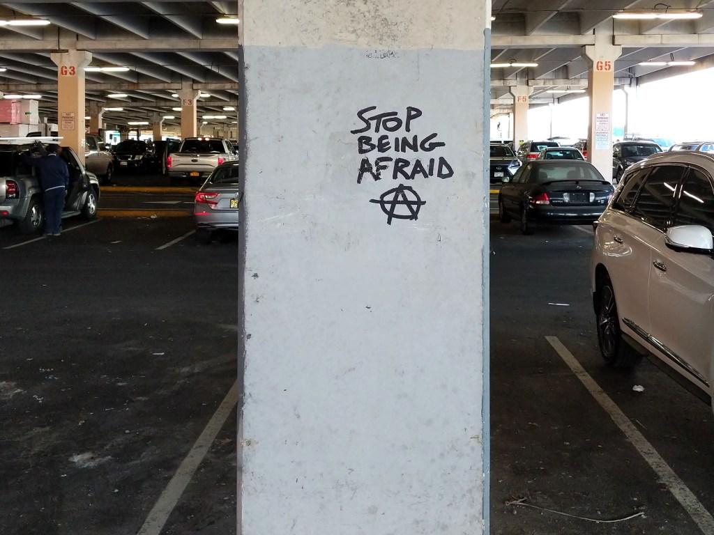 "Stop Being Afraid Ⓐ" tagged on a concrete support column in the Home Depot parking lot on 3rd Avenue in Brooklyn, NY.