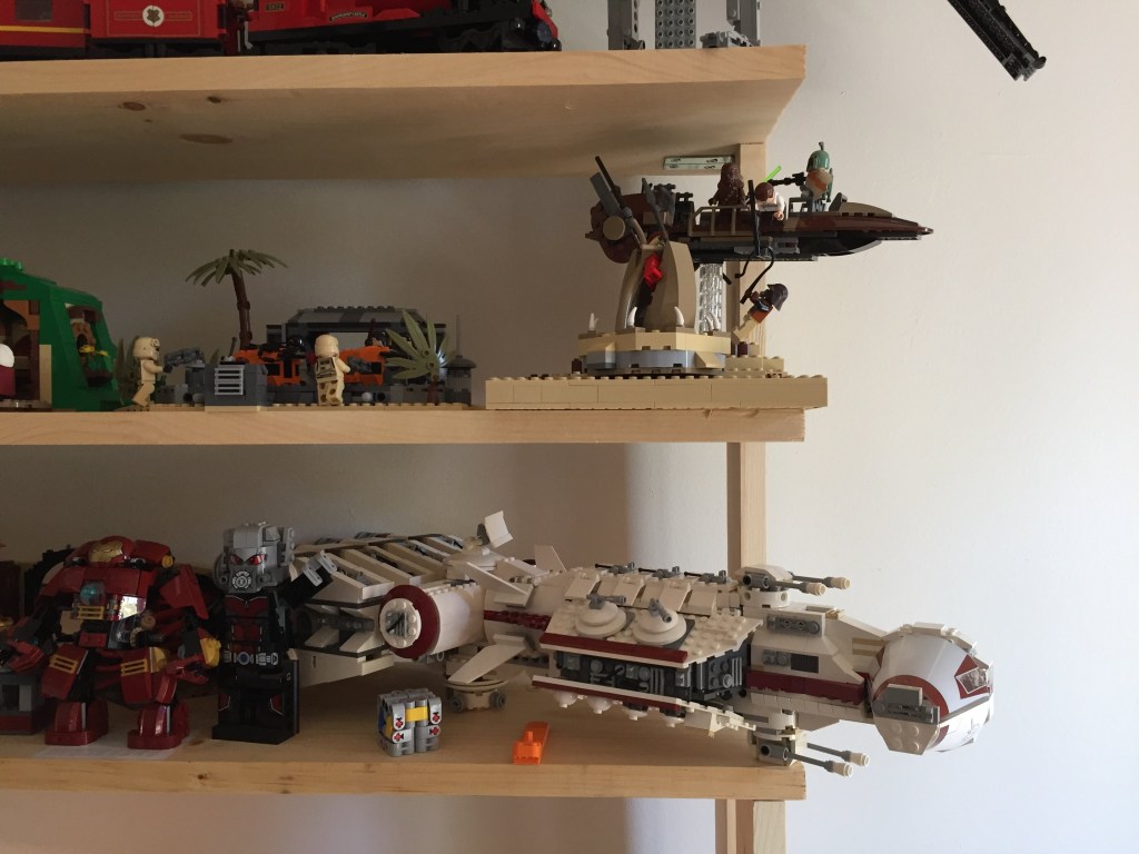 Two wooden shelves of LEGO sets from LOTR, Avengers, and Star Wars.