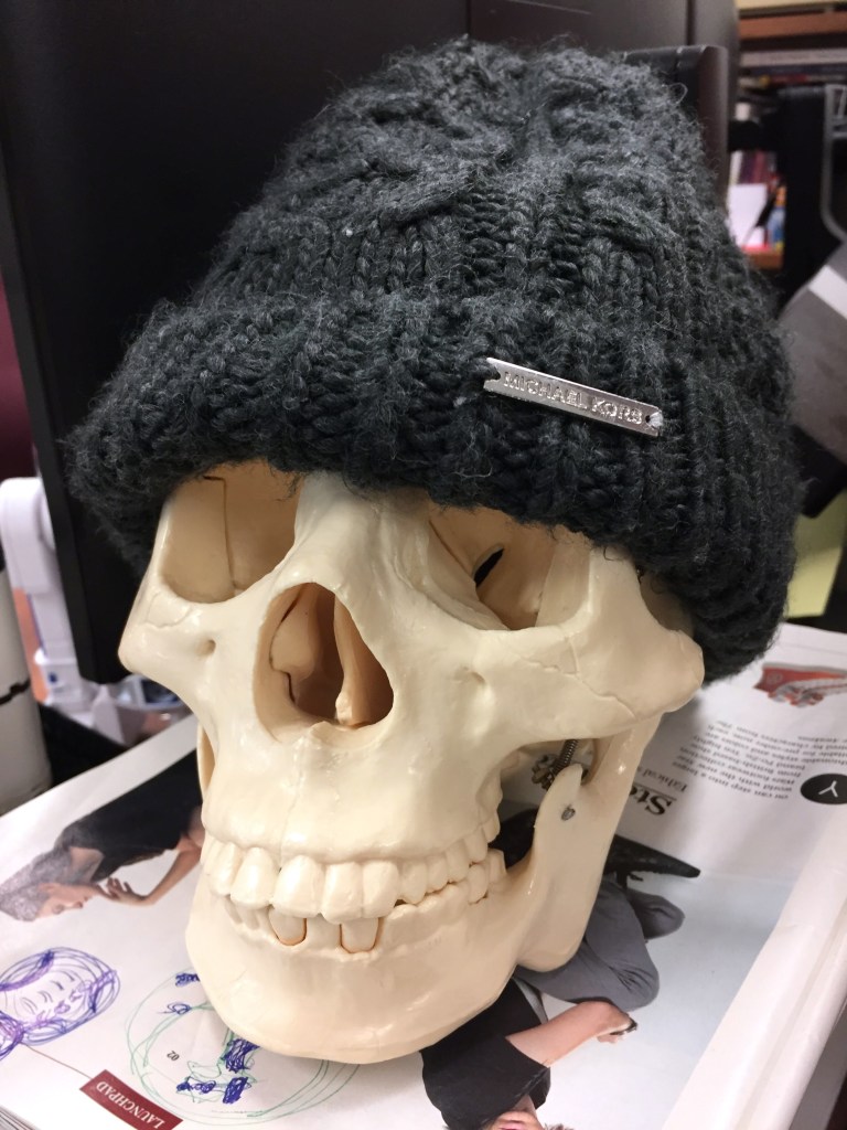 human skull model wearing a knitted Michael Kors hat
