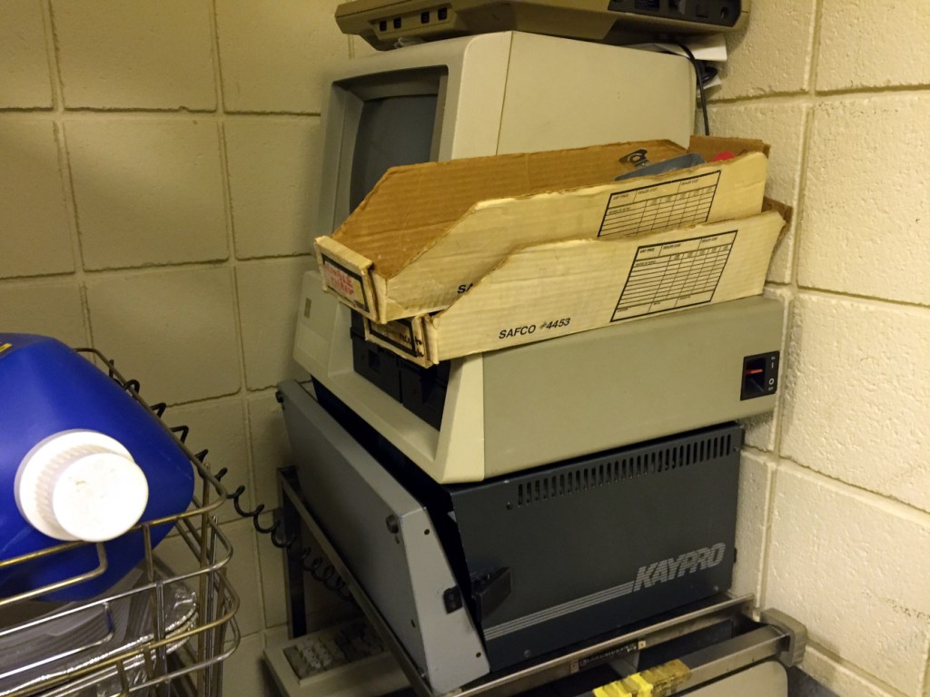 Vintage computers stacked in a corner of a closet