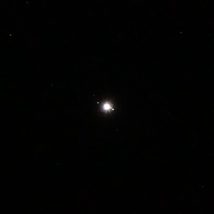 Zoom in on Jupiter and its moons in night sky image.