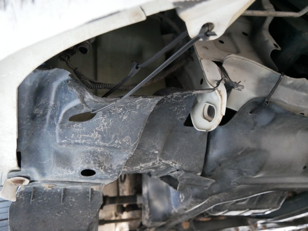 Front bumper and lower engine compartment covers held in place with zip ties on 2013 Toyota Corolla.