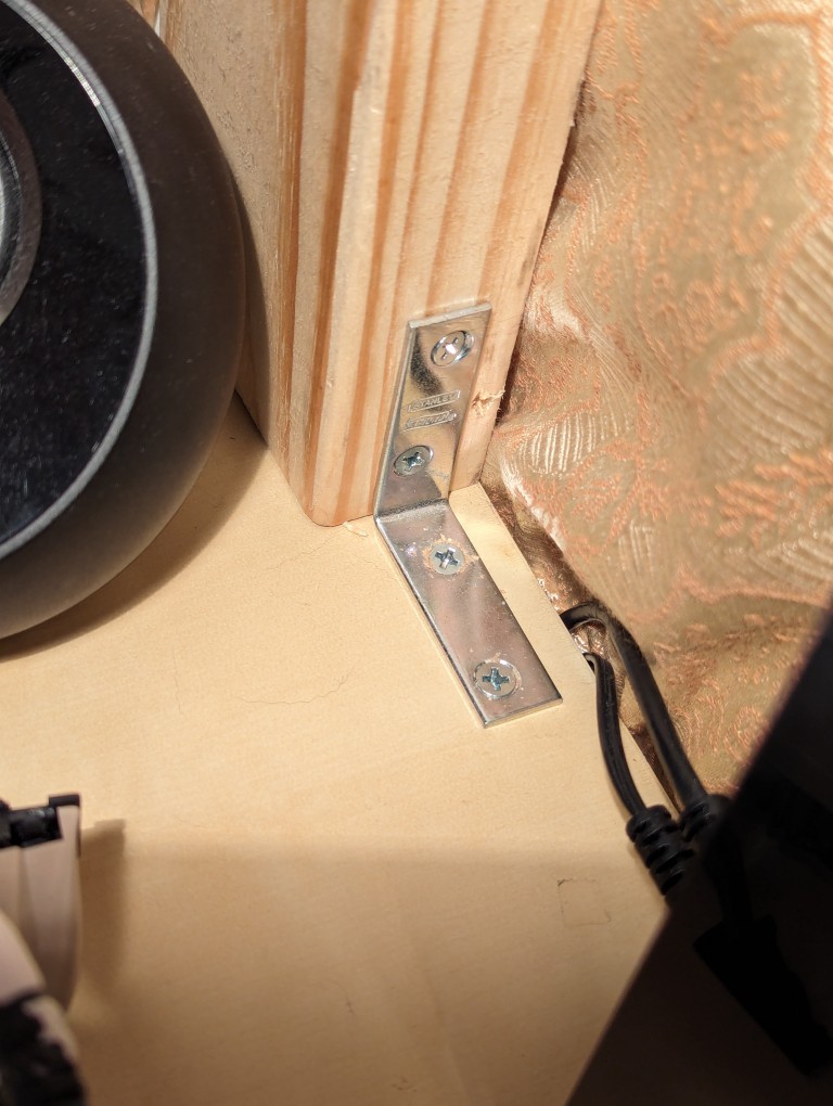 L-shaped metal bracket connecting an IKEA desk top with a 2" x 4" stud
