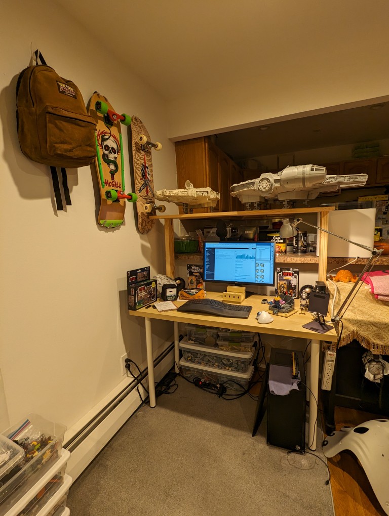 IKEA 47" desk with metal legs and DIY 12" shelf supported by two 2" x 4" x 24" studs. There are two Millennium Falcon toys on the shelf.