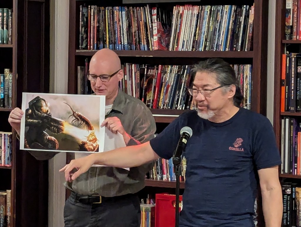 Jay Werkheiser and Frank Wu standing by a microphone and reading from a text.