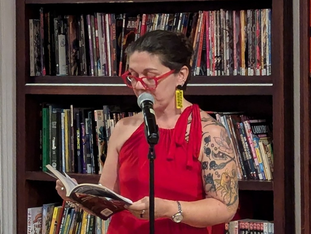 Victoria Navarra standing by a microphone and reading from a text.