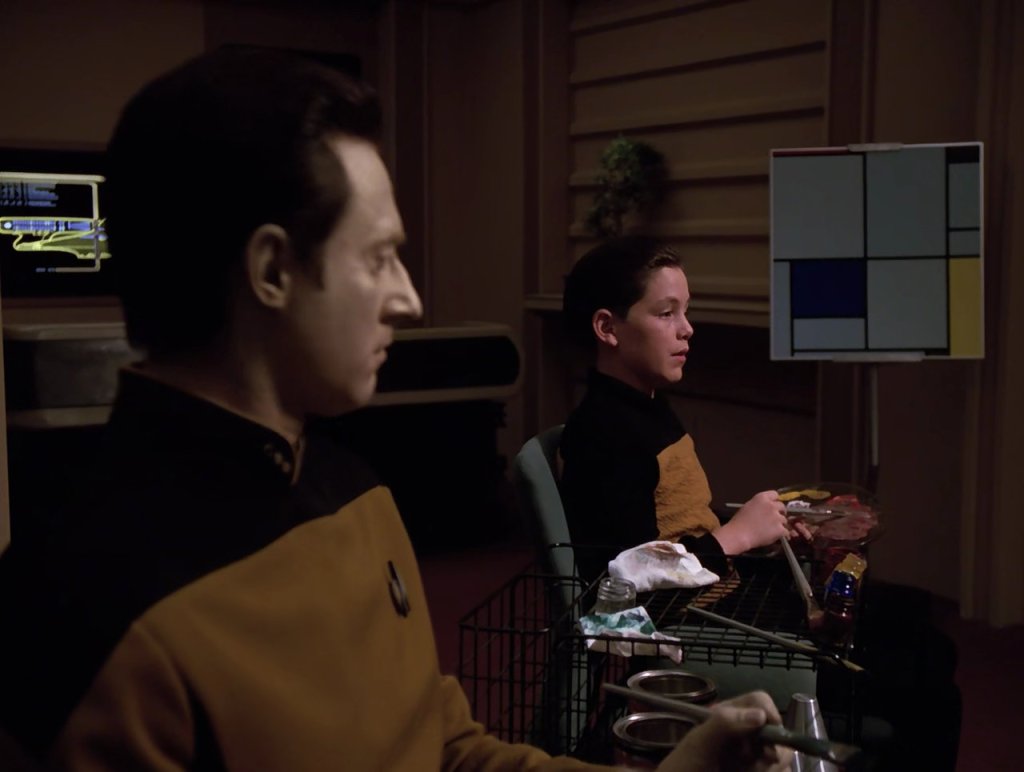 Lt. Cmd. Data seated next to Timothy. Mondrian's "Tableau I" is in the background.