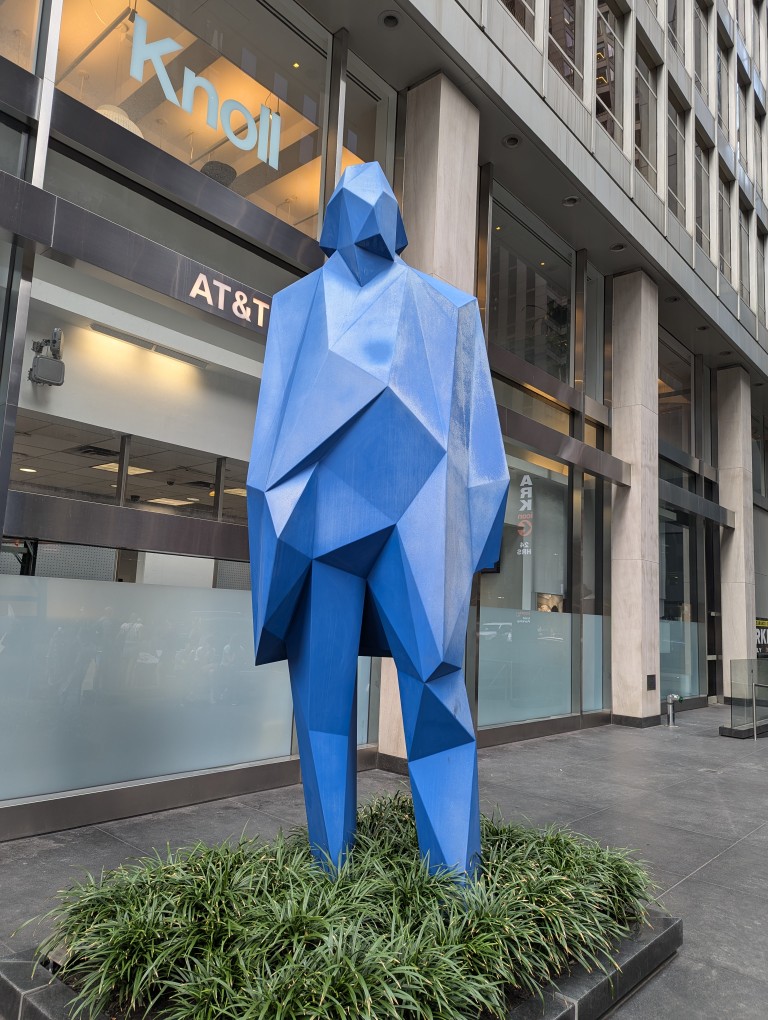 Low-resolution polygonal statue of a human figure standing on a sidewalk in Manhattan