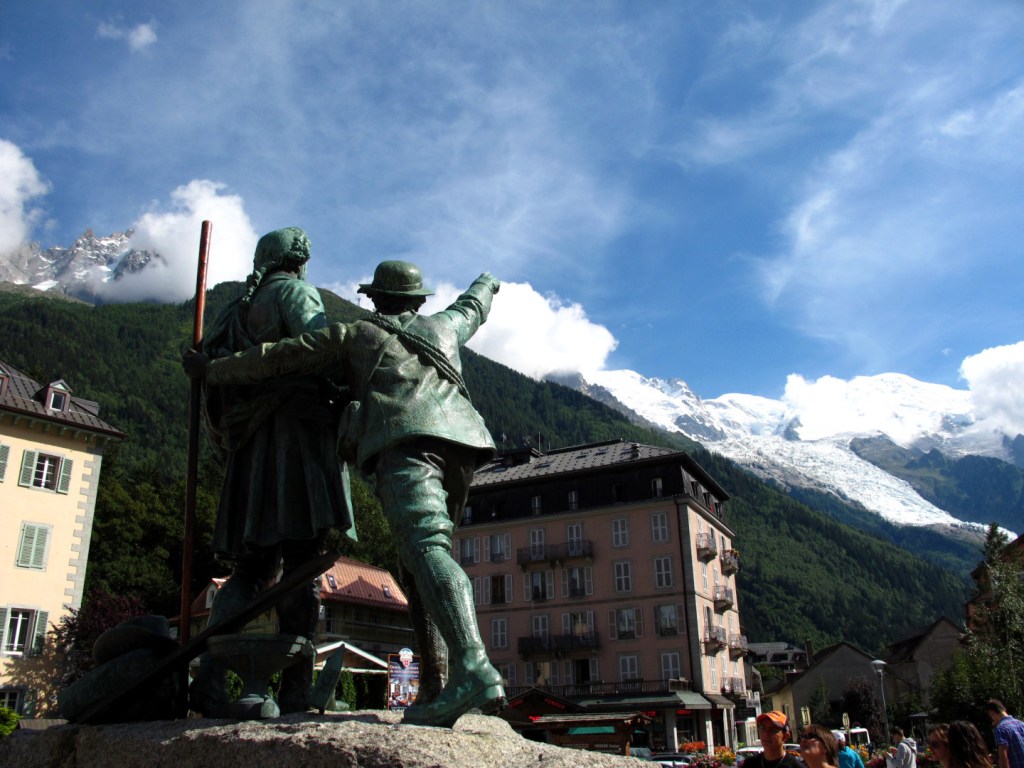 statue of two men, one of them is pointing to mont blanc in the distance.