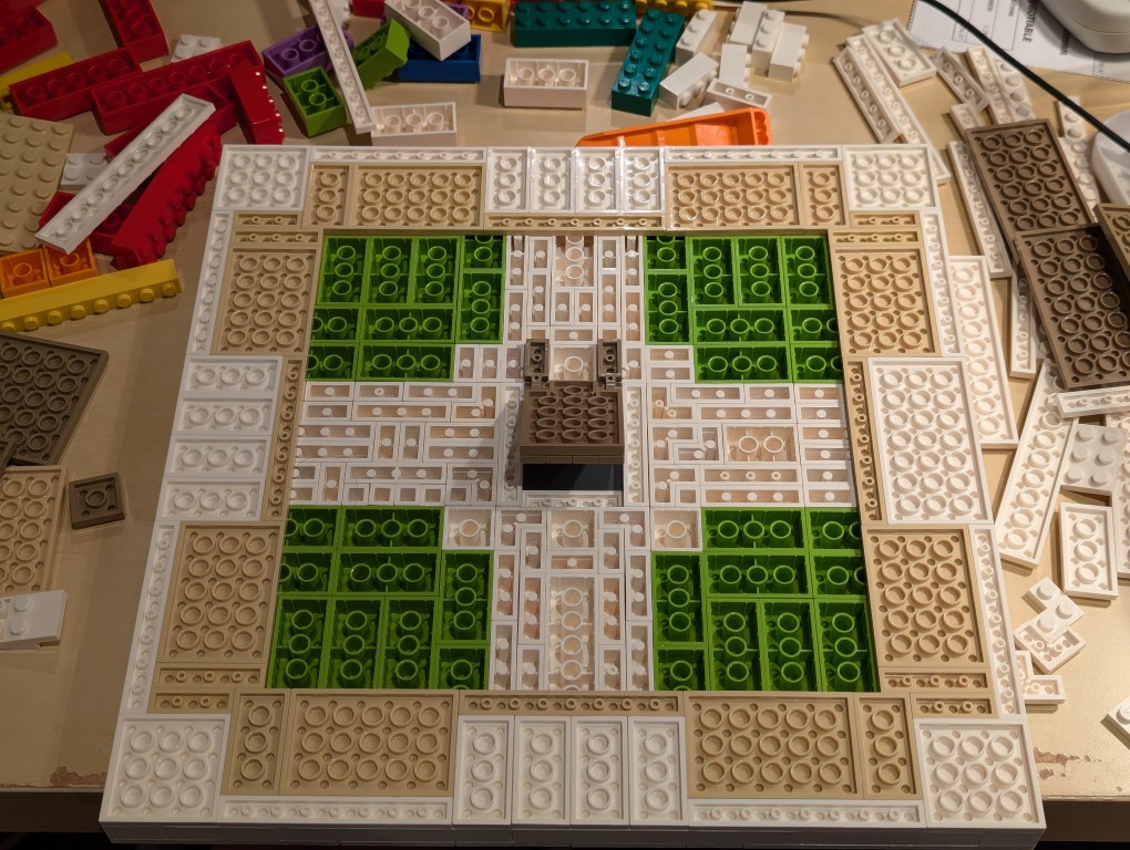 LEGO white plates in a 32x32 layout upside down with bricks filling the layout but center removed for hidden compartment and trapdoor installed