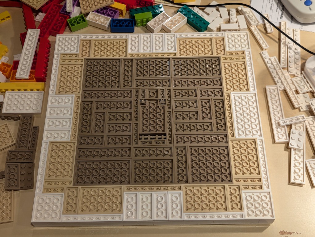 LEGO white plates in a 32x32 layout upside down with bricks filling the layout but center removed for hidden compartment