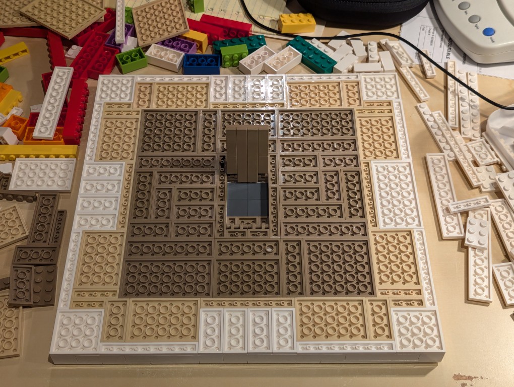 LEGO white plates in a 32x32 layout upside down with bricks filling the layout but center removed for hidden compartment with trap door open
