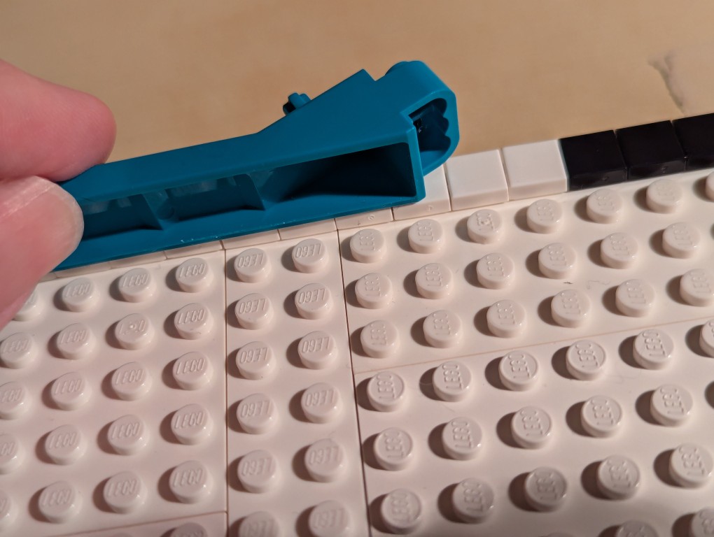 LEGO brick separator sliding along the 1x1 flat tiles to align them