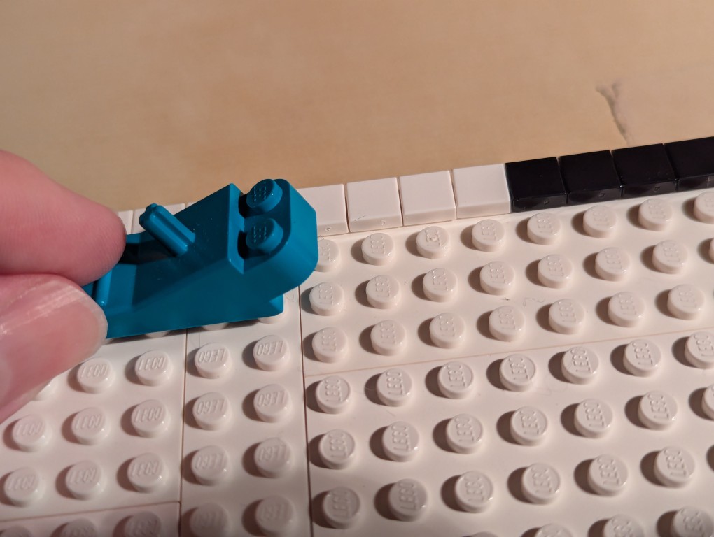 LEGO brick separator sliding along the 1x1 flat tiles to align them