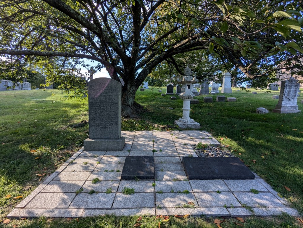 stone memorial with a japanese lantern and large tree with overarching limbs