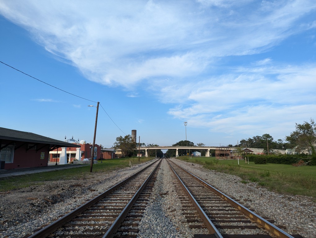 two sets of train tracks extended to the horizon and going under an roadway overpass