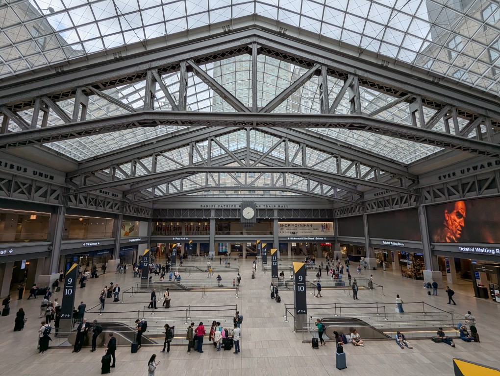 steel trusses holding up the glass roof over a floor with escalators going down