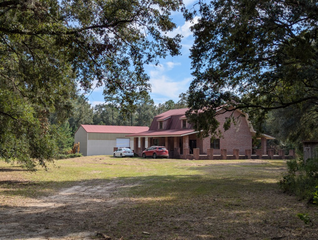 trees draping the driveway to a house and metal shop