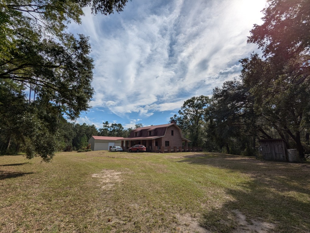 trees surrounding a house and metal shop