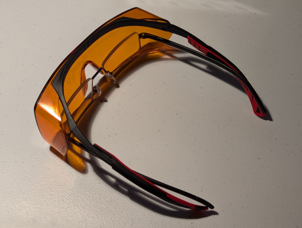 reading glasses nested inside a pair of blue blocking orange glasses