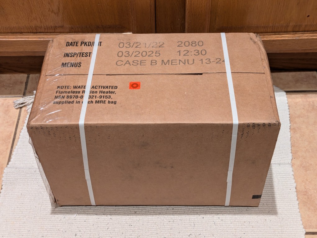 cardboard case of mres, bound with plastic straps, on floor