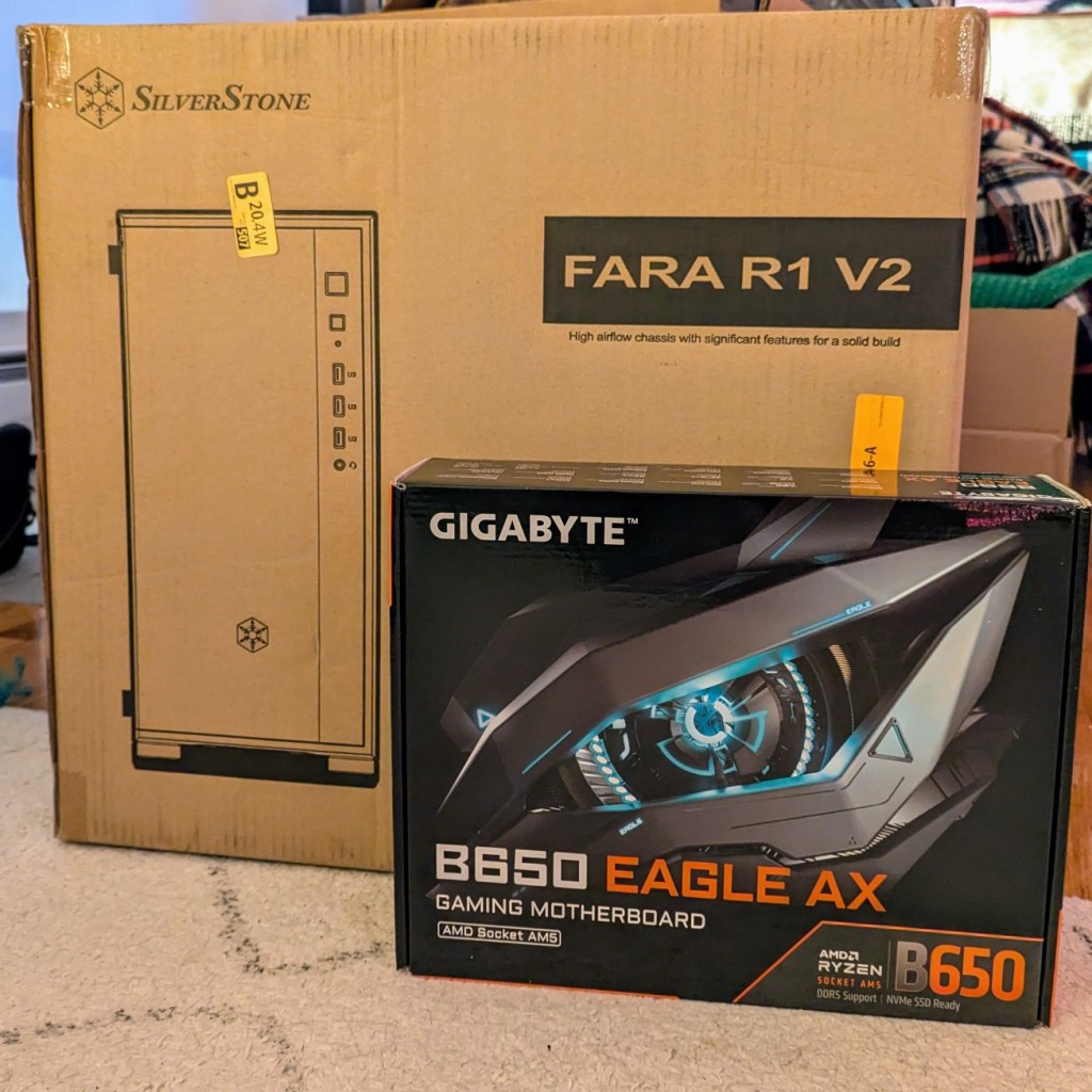 computer case in a cardboard box and a computer atx motherboard in a cardboard box