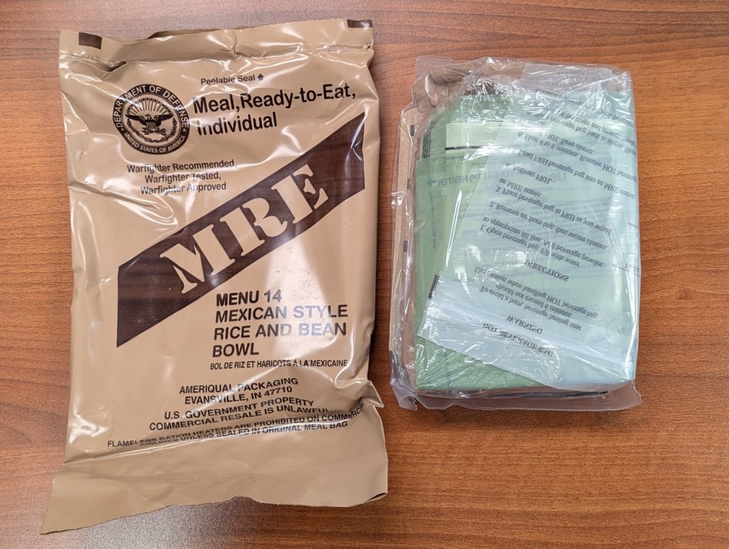 brown MRE pouch next to its contents in a clear plastic pouch