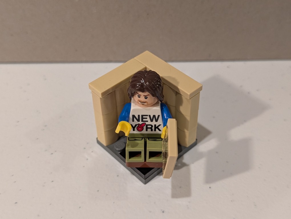 a lego mini figure sitting and reading in a tiny corner made out of bricks