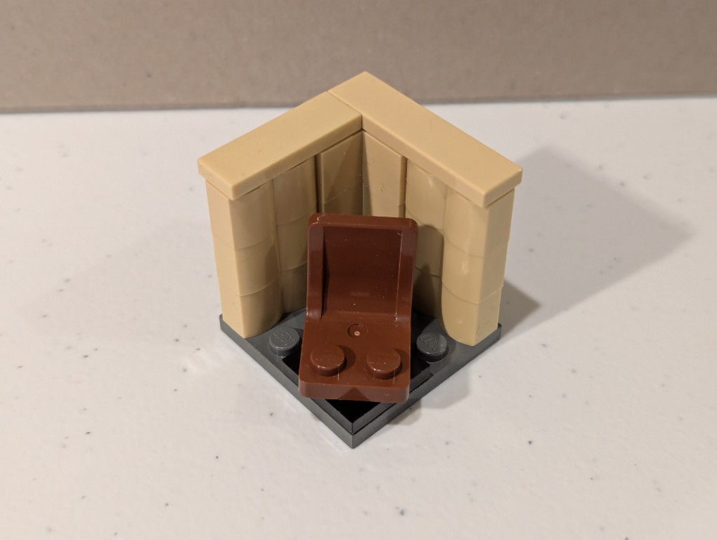 a lego mini figure sitting and reading in a tiny corner made out of bricks deconstructed