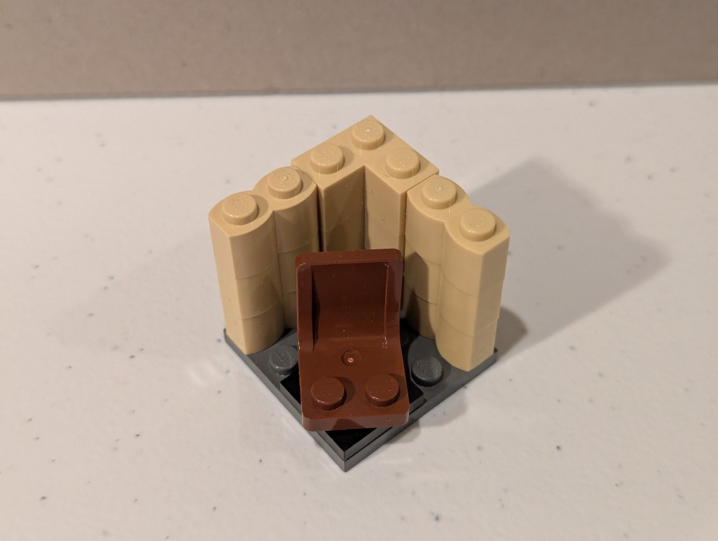a lego mini figure sitting and reading in a tiny corner made out of bricks deconstructed