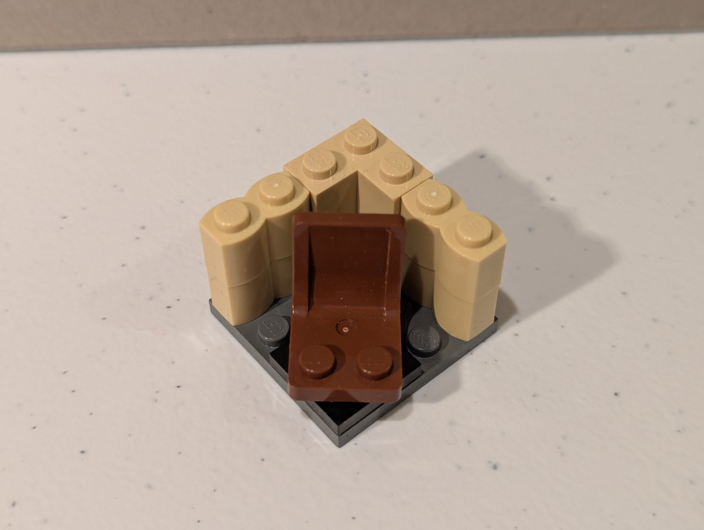 a lego mini figure sitting and reading in a tiny corner made out of bricks deconstructed