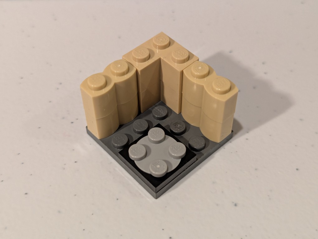 a lego mini figure sitting and reading in a tiny corner made out of bricks deconstructed
