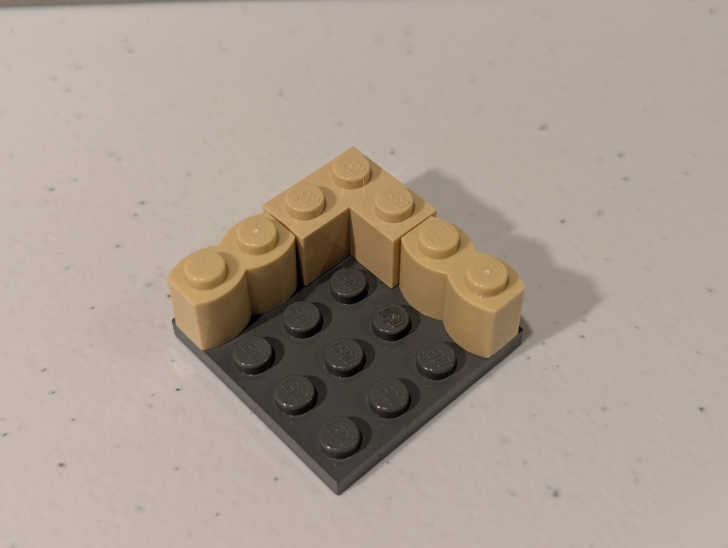 a lego mini figure sitting and reading in a tiny corner made out of bricks deconstructed