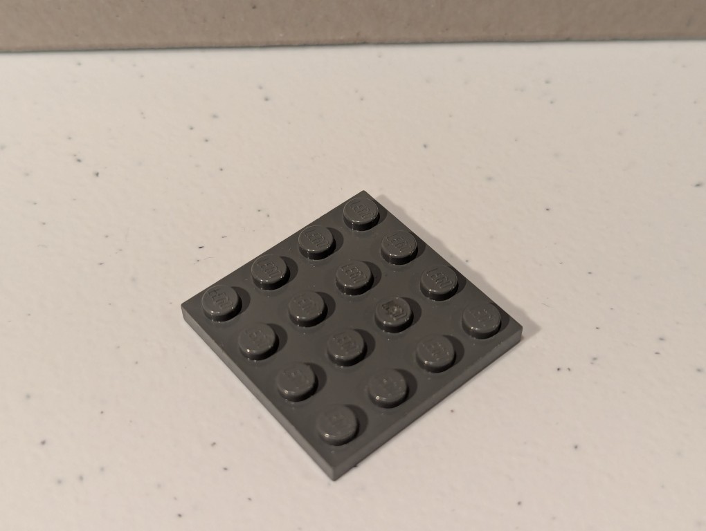 a lego mini figure sitting and reading in a tiny corner made out of bricks deconstructed