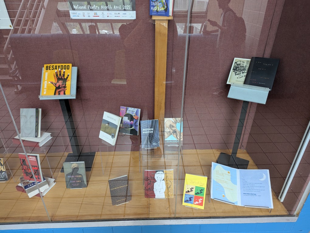 display of books and banner for national poetry month behind a large glass facade