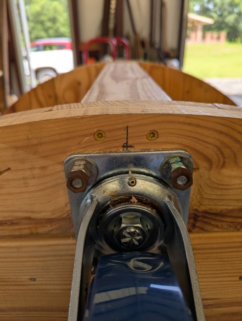 closeup of screws above caster wheels driven into 2x4