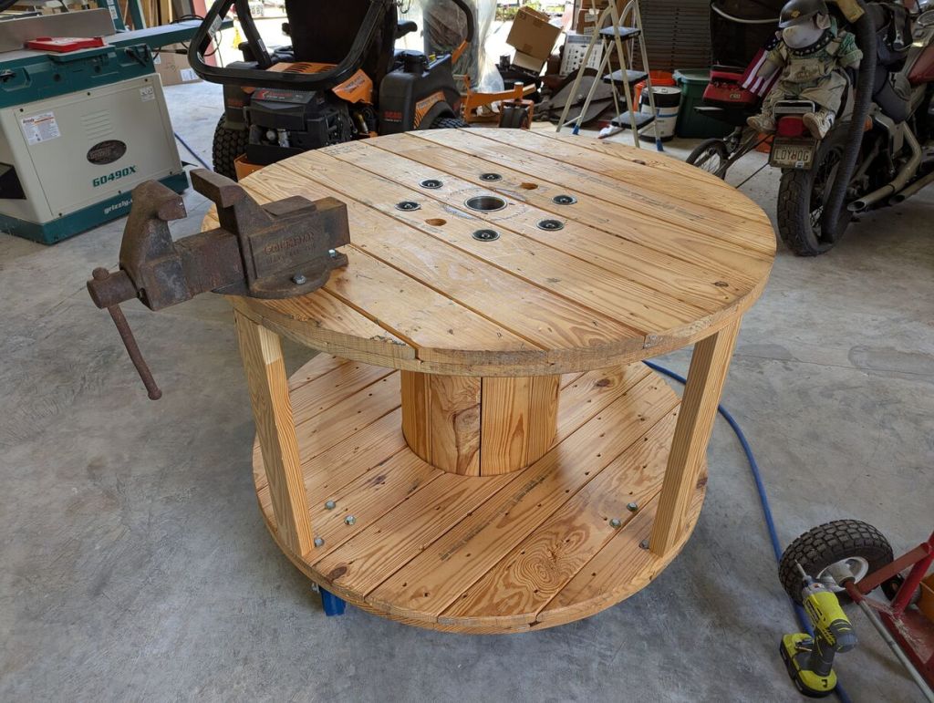 round wood workbench on caster wheels with a metal vice mounted on top