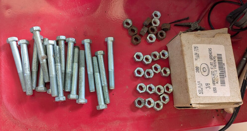 bolts, nuts, and washers on a red metal surface