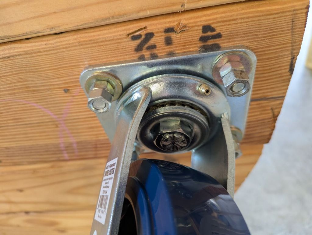 closeup of 2 sets of nuts on each bolt holding caster wheels on bottom of workbench