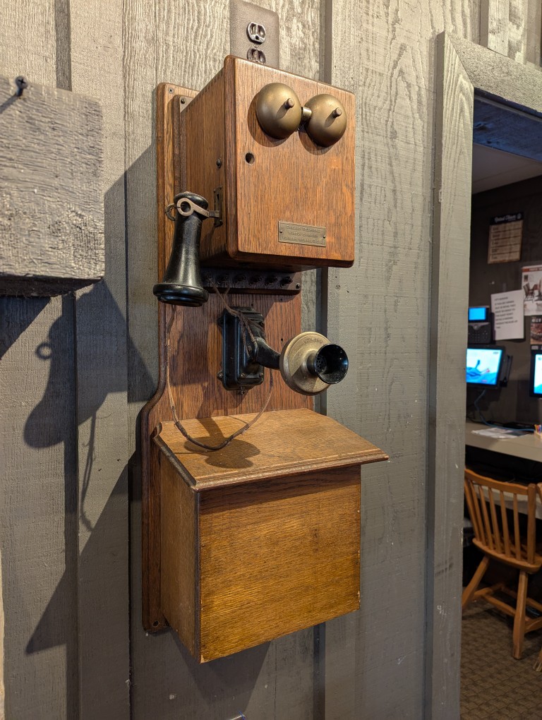 crank-style telephone mounted on wood wall