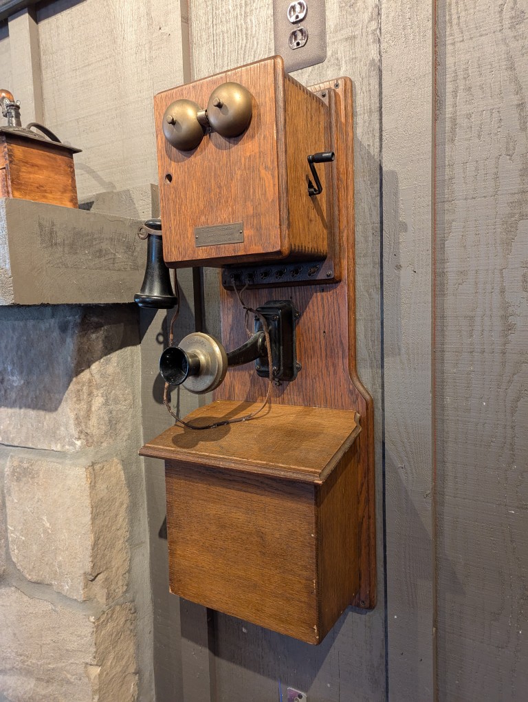 crank-style telephone mounted on wood wall