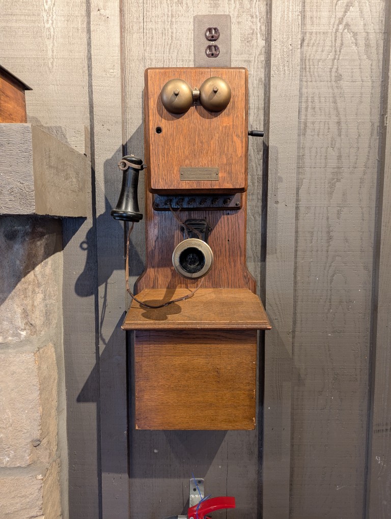 crank-style telephone mounted on wood wall
