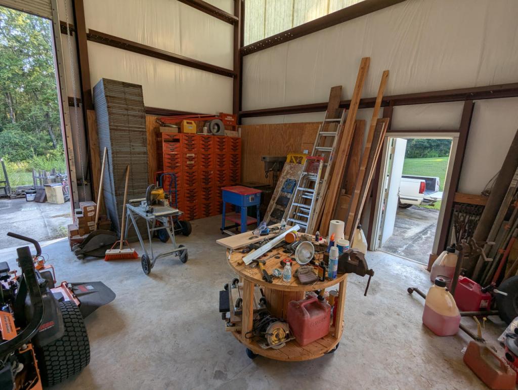inside corner of a metal building with tools, equipment, ladders, and other work related items