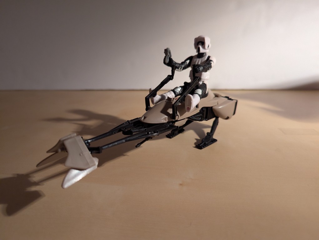 kenner speeder bike toy with a biker scout sitting on top holding the handles and a blaster pistol, 3/4 view