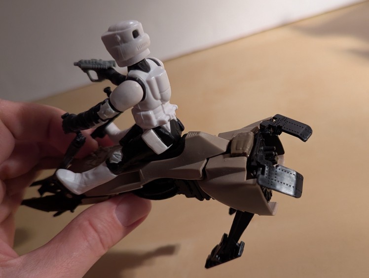 kenner speeder bike toy with a biker scout sitting on top holding the handles and a blaster pistol, lifted with engine flaps open