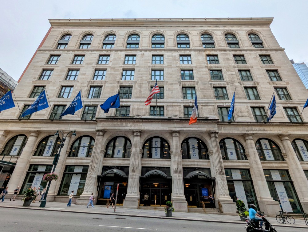 front entrance of the cuny graduate center, multi-story building with stone facade and columns rising from the sidewalk to the second floor