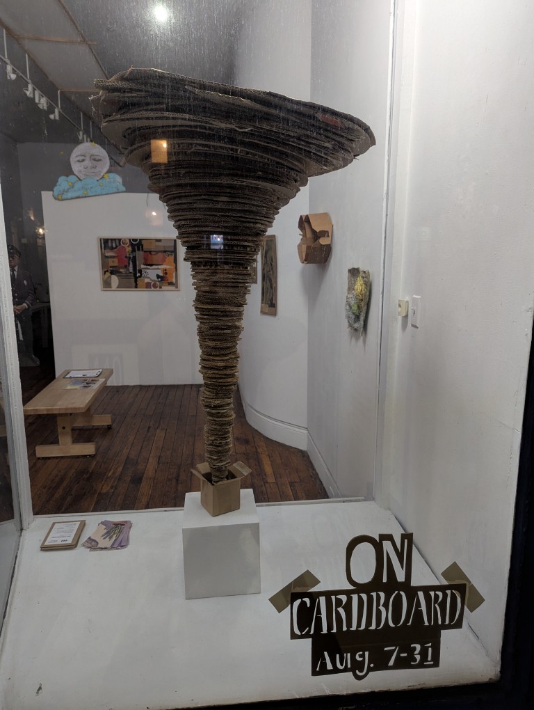a cardboard tornado erupts out of a tiny cardboard box