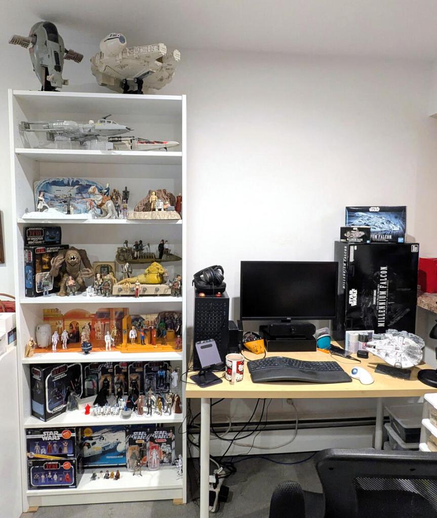 Star Wars vintage and modern action figures and vehicles on a bookshelf and desk.